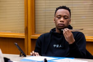 A student examines his newly created quill pen.
