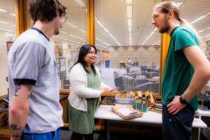 Three students work with a letterpress in the BookLab.