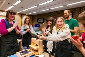 Five students cheer after creating a print on a press in NIU's BookLab.